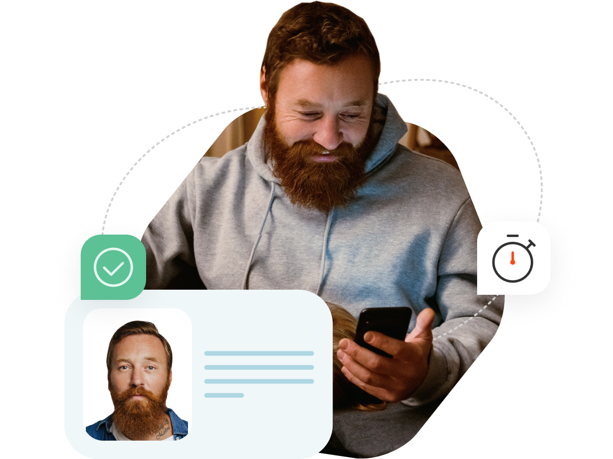 A man with a beard and in a grey hoodie is looking down at his phone he is holding in his hand