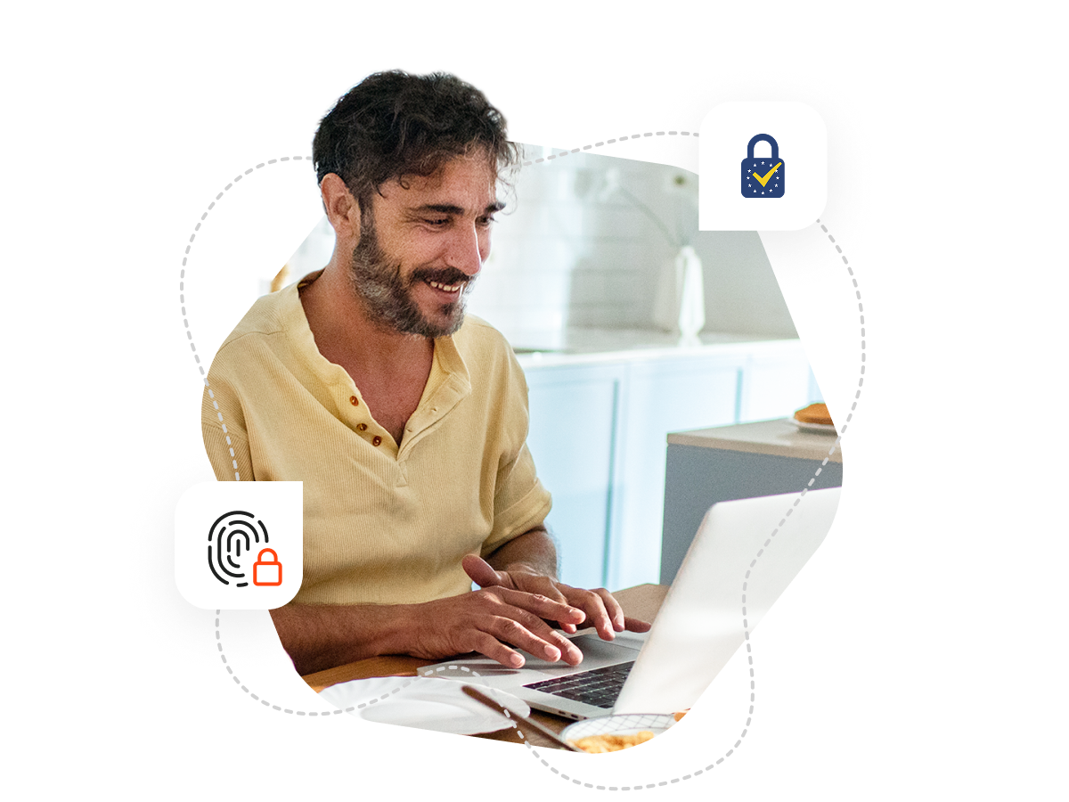 A man with black hair and beard is sitting at his desk and typing on his laptop