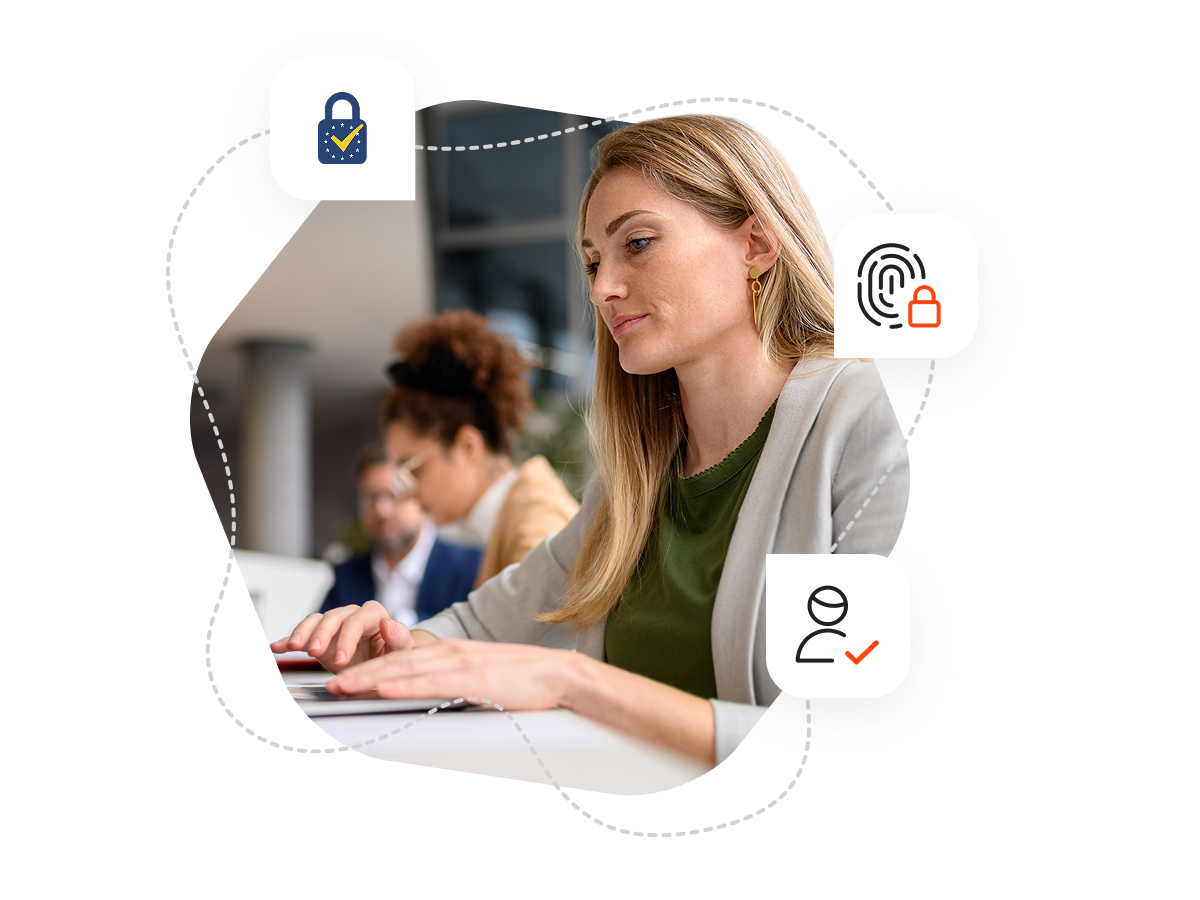 A woman with long blonde hair is sitting at a desk and typing on her laptop